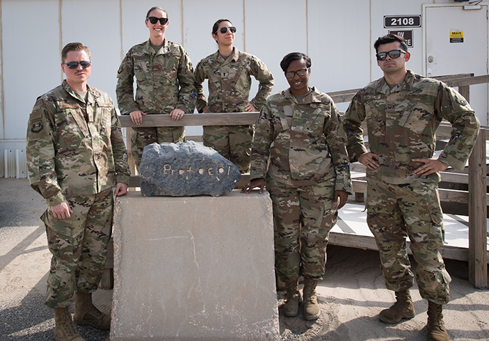 The 386th Air Expeditionary Wing protocol team pose for a photo outside their office at Ali al Salem Air Base, Kuwait, Aug. 15, 2019. Left to Right: Tech. Sgt. Tyler Shepherd, NCO-in-charge of protocol, deployed from Moody Air Force Base, Georgia; Capt. Rosa-Mae Bacon, chief of protocol, deployed from Davis-Monthan AFB, Arizona; 1st Lt. Kassandra Prusko, deputy chief of protocol, deployed from Andrews AFB, Maryland; Staff Sgt. Courtney Lansden, protocol specialist, deployed from Offutt AFB, Nebraska; and Tech. Sgt. Diego Casillas, superintendent of protocol; deployed from Los Angeles AFB, California. (U.S. Air Force photo by Tech. Sgt. Daniel Martinez)